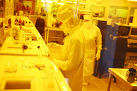 Eine Mitarbeiterin fertigt in einem Reinraumlabor unter Gelblicht Sensoren für Beatmungsgeräte