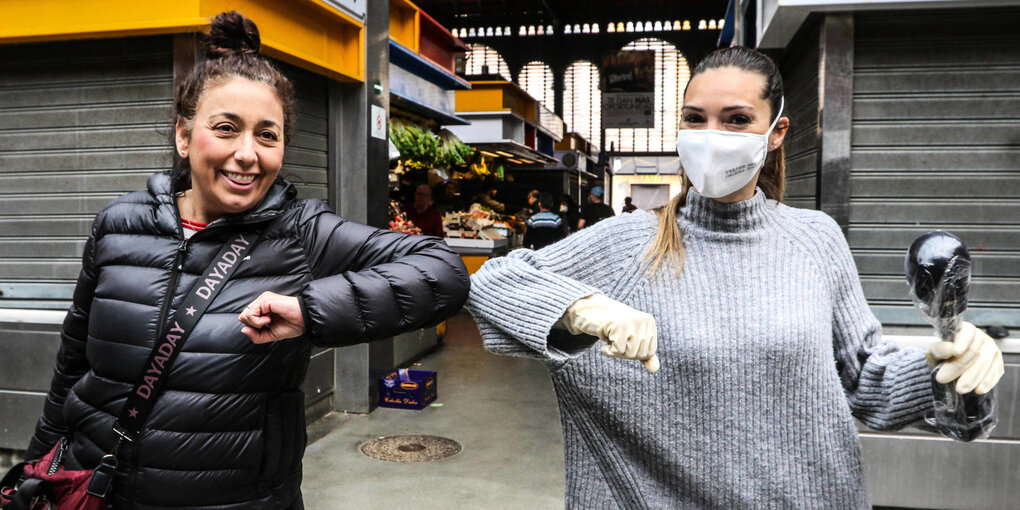 Zwei Frauen begrüßen sich mit dem Ellbogencheck