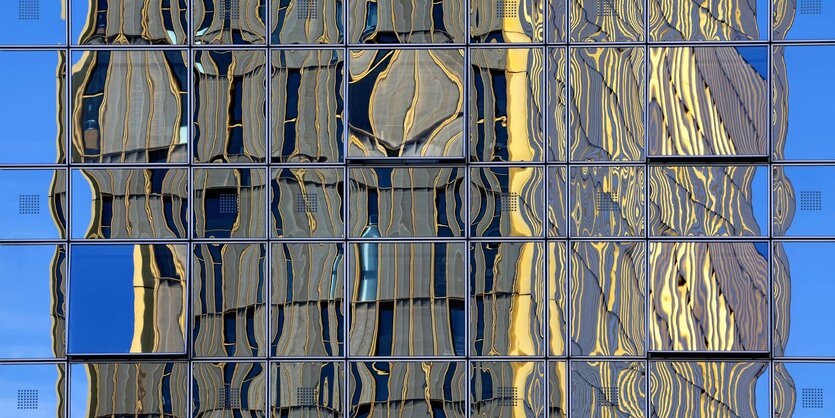 Ein Hochhaus spiegelt sich in einer Fensterfront.