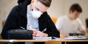 Ein Schüler mit Mundschutz bei einer Prüfung.