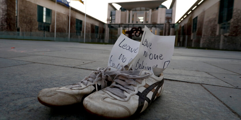 zwei Schuhe mit einem zettel stehen vor dem Kanzlerinnenamt