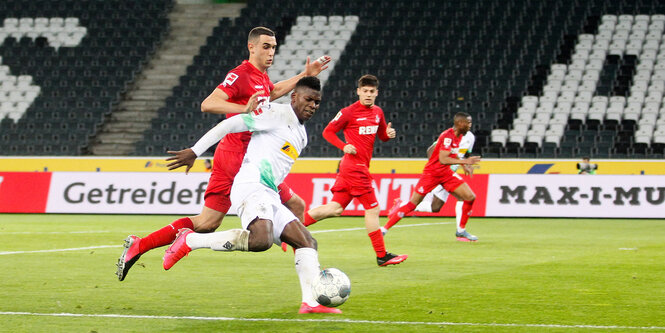 Der Mönchengladbacher Breel Embolo (r) und der Kölner Ellyes Skhiri kämpfen um den Ball. Das Spiel findet wegen des Coronavirus ohne Zuschauer als Geisterspiel statt