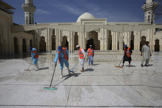 Menschen in Schutzanzügen in einer Moschee in Peshawar, Pakistan. Menschen in Schutzanzügen in einer Moschee in Peshawar, Pakistan.