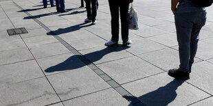 Schatten von Menschen, die in einer Schlange stehen.