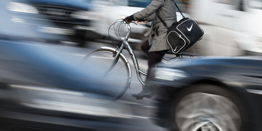 Radfahrerin vor schnell vorbei sausenden, verwischten Autos