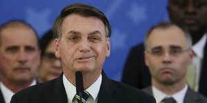 Brasiliens Präsident zieht ein schiefes Gesicht, während er in ein Mikrofon spricht.