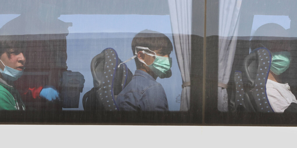 Kinder mit Schutzmasken sitzen im Bus