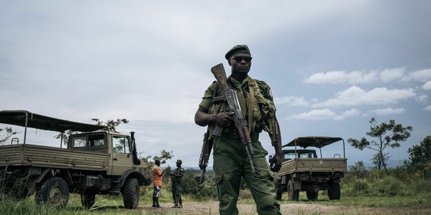 Ein Ranger steht im Virunga Nationalpark vor zwei LKWs
