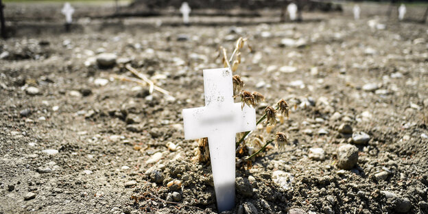 Ein kleines weisses Kreuz auf Friedhof