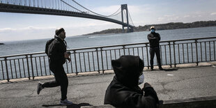 Ein Jogger und Menschen mit Mundschutz vor einer Brücke