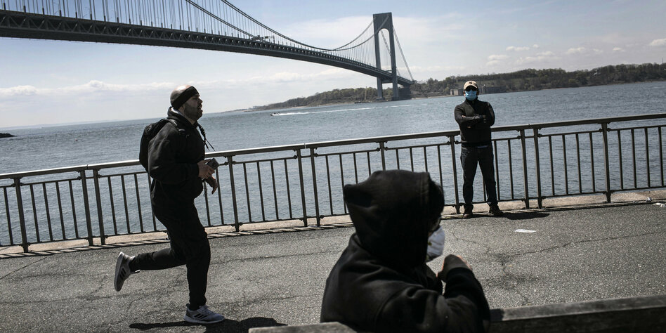Ein Jogger und Menschen mit Mundschutz vor einer Brücke
