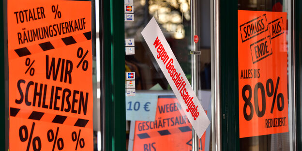 Ein Ladenfenster mit "Wir schließen"-Postern Ein Ladenfenster mit "Wir schließen"-Postern