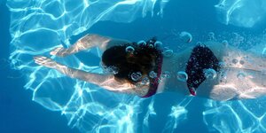 Luftblasen und eine Schwimmerin in türkisblauem Wasser