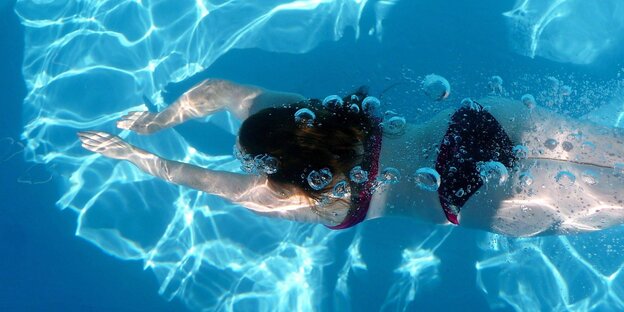 Luftblasen und eine Schwimmerin in türkisblauem Wasser