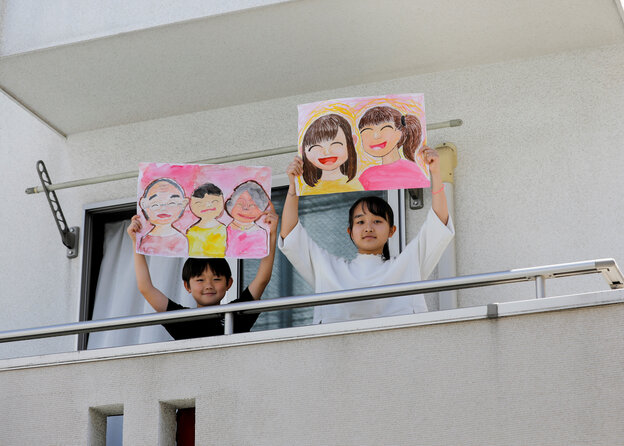 Zwei Kinder mit selbstgemalten Bildern auf einem Balkon