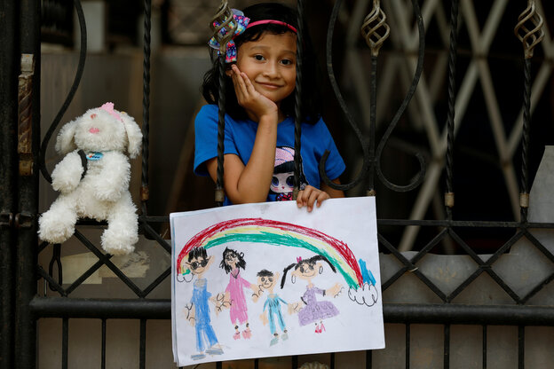Ein Kind mit einem selbstgemalten Bild auf einem Balkon