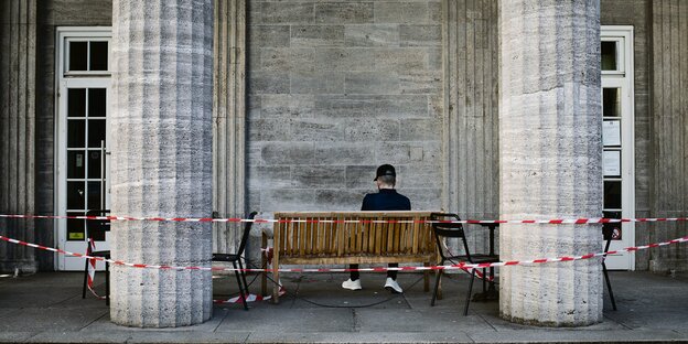Ein Mann sitzt hinter einem Absperrband auf einer Bank in der Hamburger Innenstadt.