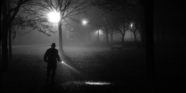 Ein Mann alleine unterwegs in der Nacht mit einer Taschenlampe