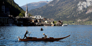 Berglandschaft um einen See, eine Frau rudert ein Boot