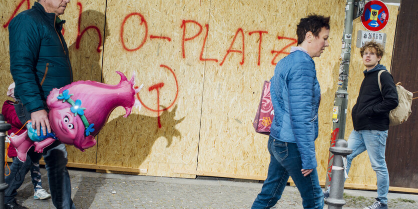 Ein Maqnn mit einem Luftballon vor ein gesprühten 1. Mai Aufruf.