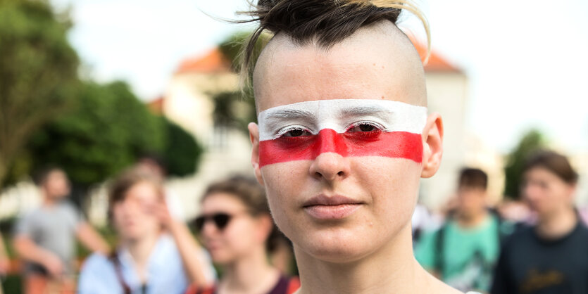 eine junge Frau mit den polnischen Nationalfarben weiß und rot im Gesicht