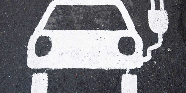 Ein Symbol eines Elektroautos markiert einen Parkplatz neben einer E-Ladesäule.