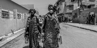Frauen mit Mundschutz tragen im Senegal Lebensmittel-Spenden nach Hause
