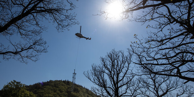 Ein Träger für die Baumschwebebahn Harz hängt für die Montage an einem Hubschrauber.