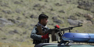 Ein Afghanischer Polizist hinter einem montierten Maschinengewehr