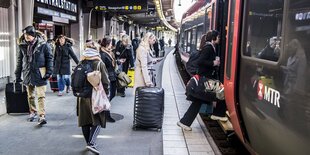 Menschen auf einem Bahnsteig, die gerade in einen Zug einsteigen