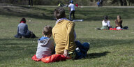 Ein Frau und ein Kind sitzen auf einer Parkwiese