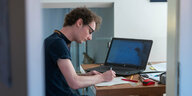 Ein Student, arbeitet zu Hause neben einem Laptop