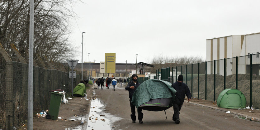 Ein Feuerwehrmann in Schutzkleidung misst die Temperatur von Migranten, die vor der Küste von Calais aufgegriffen wurden.