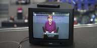 die Kanzlerin bei einer Bundestagsrede auf einem Fernsehschirm