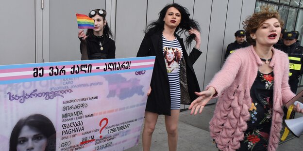 Drei Angehörige der LGBTQUI-Minderheit in Georgien protestiert mit einem Schild