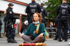 Eine Frau sitzt im Schneidersitz auf einer Matte inmitten von stehenden Polizisten