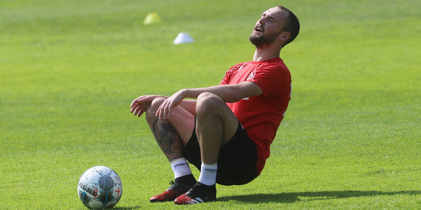 Fußballer beim Training lässt sich auf den Rasen fallen