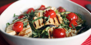 Ein Teller mit einem Salat mit Kirschtomaten, darauf veganer Halloumikäse