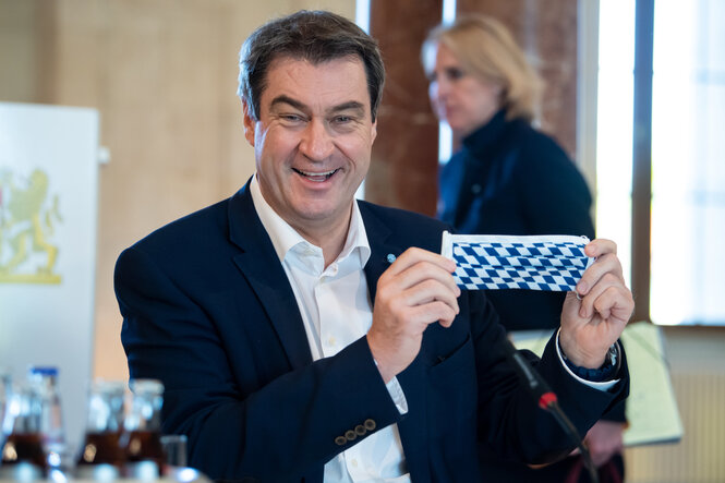 Markus Söder zeigt Mundschutz mit Rauten