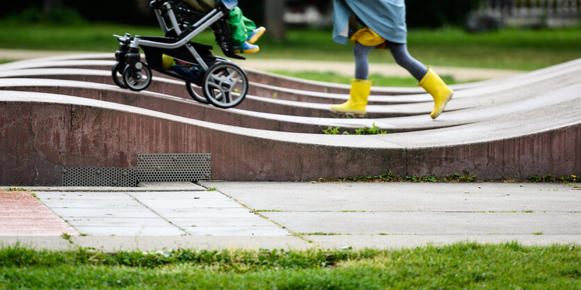 Ein Kinderwagen wird über kleine Wellen aus Stein geschoben