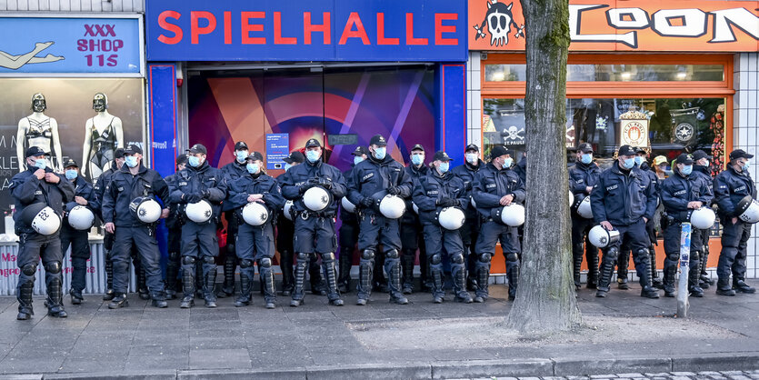 Polizisten in Schutzausrüstung stehen vor einem Laden