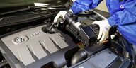 Ein Mechaniker reguliert einen EA189 Motor eines VW Fahrzeugges