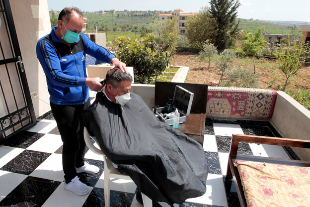 Ein Mann schneidet einem anderen Mann auf einem Balkon die Haare