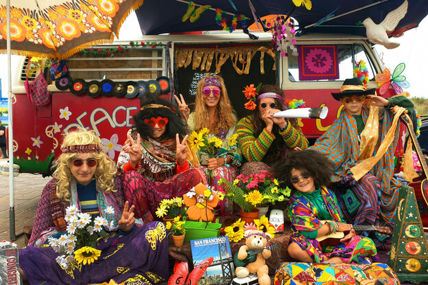 Eine Gruppe Hippies vor einem bunten VW-Bus
