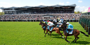 Jockeys starten mit ihren Pferden auf der Galopp-Rennbahn