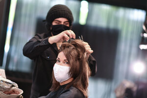 eine Frau sitzt mit Maske beim Frisör