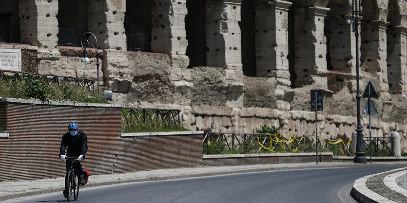 Ein mann fährt mit dem rad am Collosseum vorbei