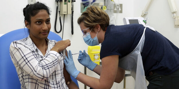 Eine medizinische Mitarbeiterin der Oxford Universität setzt einer Probandin eine Injektion