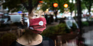 chinesische Frau mit Mundschutz am Fenster
