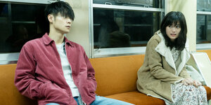 Ein Mann und eine Frau sitzen auf einer Bank in einer U-Bahn.